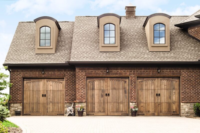 large home in san antonio with three Wayne-Dalton 7000 Custom Wood Garage Doors that are colored brown and on a red brick home