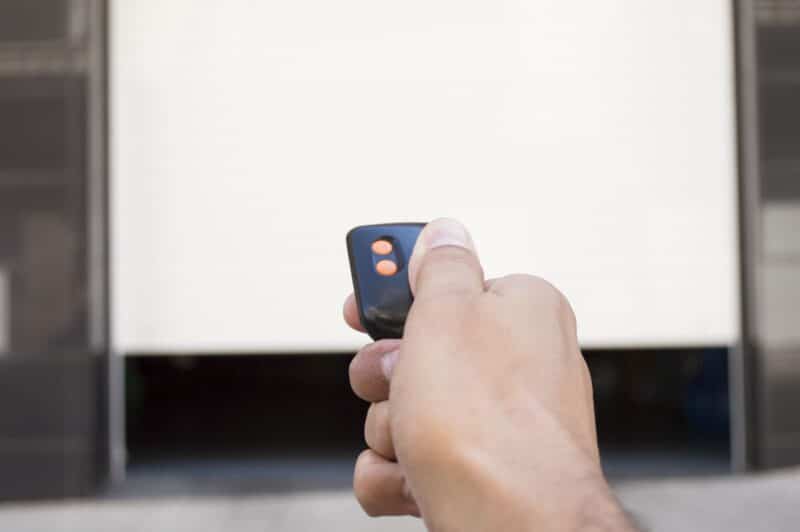 hand pressing garage remote for garage door opener
