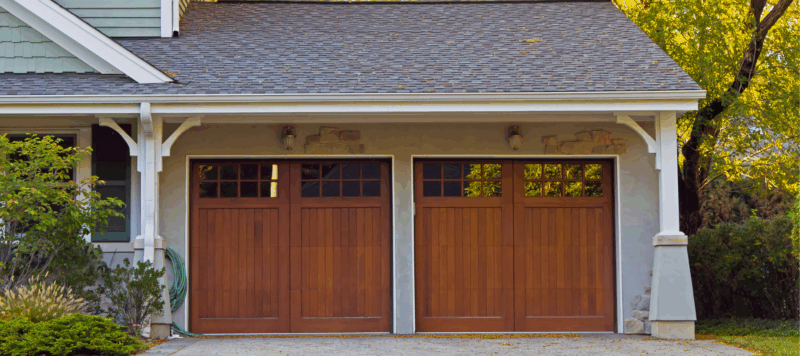 Modern double wooden carriage house garage doors with windows on a suburban home, ideal for garage door opener installation.