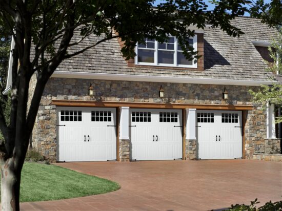 three white faux wood grain style residential garage doors on a stone home in san antonio