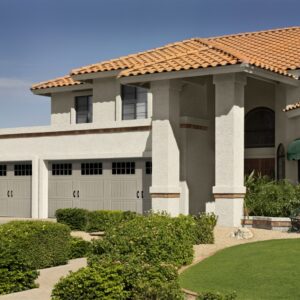 large spanish style home with three faux wood grain style residential garage doors