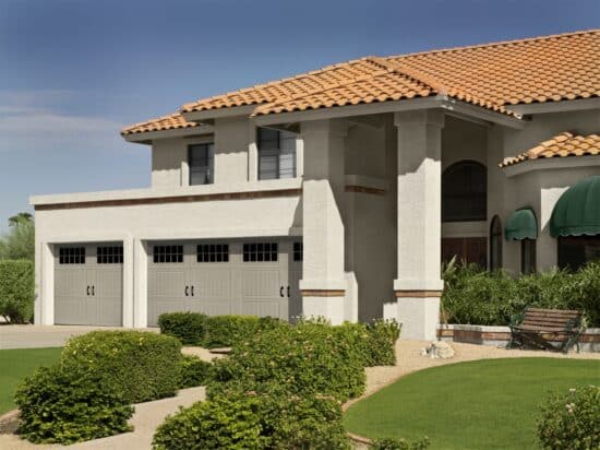 large spanish style home with three faux wood grain style residential garage doors