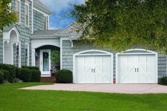 large blue home in san antonio with two white faux wood grain style residential garage doors