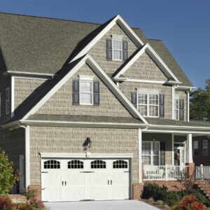 front view of a red brick and brown textured home with one white amarr classica, carriage style residential garage door beside the front porch