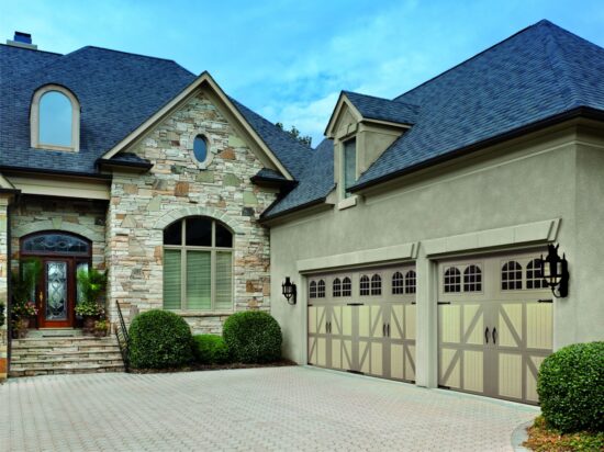 large home in san antonio with two large faux wood grain style residential garage doors with yellow and grey features