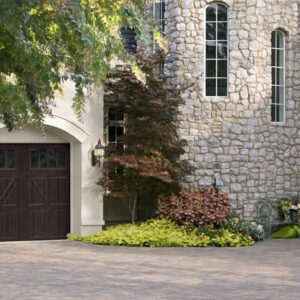 large stone home in san antonio with a dark brown faux wood grain style residential garage door with eight long paneled windows on the top row