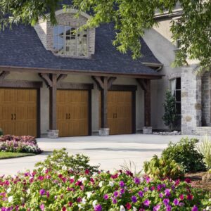 three brown faux wood grain style residential garage doors on a large stone home in san antonio