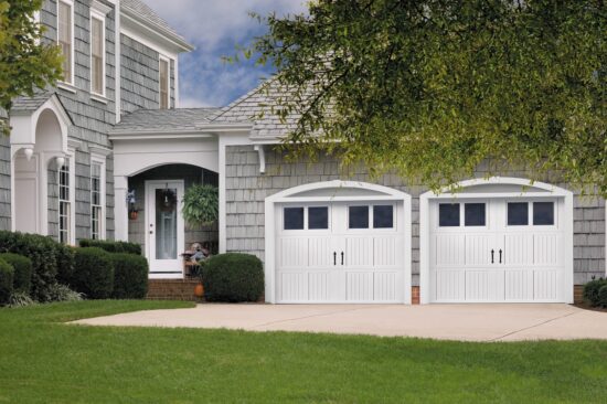 light grey/blue house with two white amarr classica, carriage style residential garage doors that have arched windows on the top row
