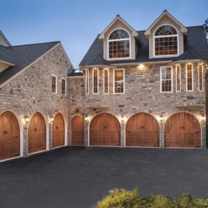 large stone home with six clopay canyon ridge, faux wood grain style residential garage doors