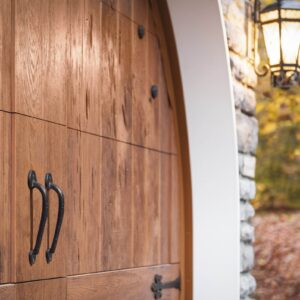 closeup of a stone home with a clopay canyon ridge, faux wood grain style residential garage door with black handles and black accents