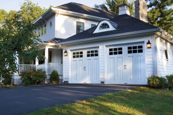 all white home with two clopay canyon ridge, faux wood grain style residential garage doors