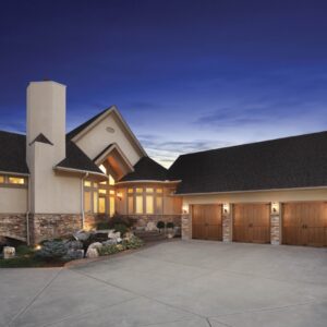 zoomed out view of a home in san antonio at dusk with three clopay canyon ridge, faux wood grain style residential garage doors
