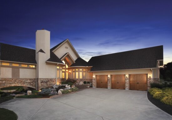zoomed out view of a home in san antonio at dusk with three clopay canyon ridge, faux wood grain style residential garage doors