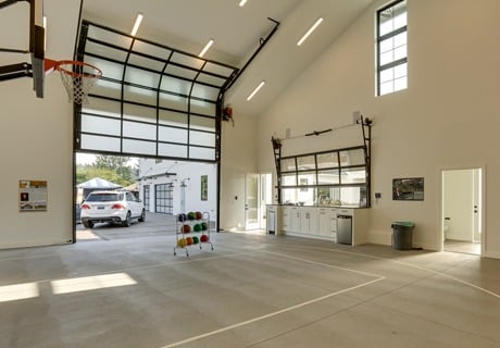 interior view of a home gym with a large clopay avante AX, modern style, full-view aluminum residential garage door as well as a smaller one for a kitchen area