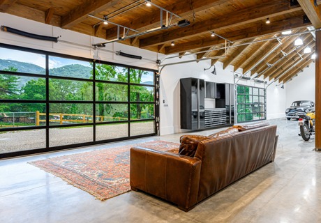 view of a clopay avante AX, modern style, full-view aluminum residential garage door from the inside with a couch and other leisure areas showing a garage