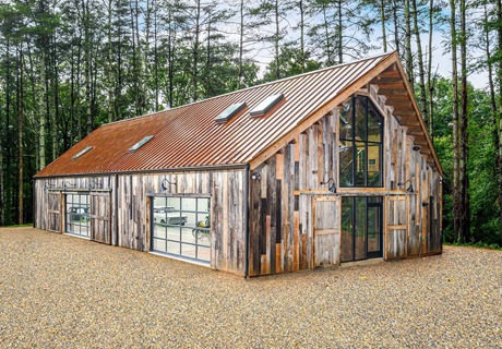 wide view of a barn-looking venue that has two clopay avante AX, modern style, full-view aluminum residential garage doors