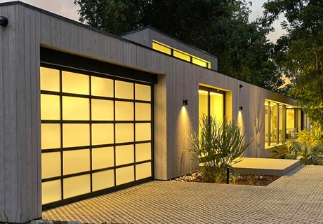 ultra modern home with a clopay avante AX, modern style, full-view aluminum residential garage door with a yellow light shining through it