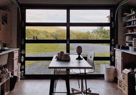 view from the interior of a smaller building looking outside through the clopay avante AX, modern style, full-view aluminum residential garage door