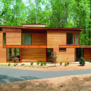 large modern wooden home with a clopay canyon ridge, modern style residential garage door set in a wood setting with tall trees
