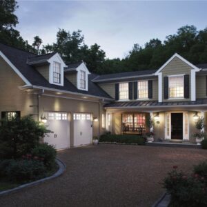 large home at dusk with two white clopay gallery, faux wood grain style, residential garage doors