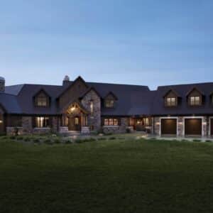 wide view of a large home at dusk with three dark brown clopay gallery, faux wood grain style, residential garage doors