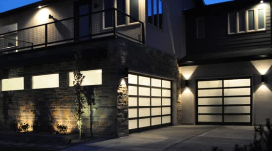home at night with outdoor lighting showing two martin elite athena, modern style, full-view aluminum residential garage doors