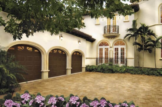 large spanish style home with three arched clopay premium classic series, faux wood style residential garage doors
