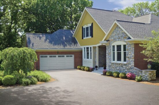 a partially red brick home with a clopay premium classic series, traditional style residential garage door