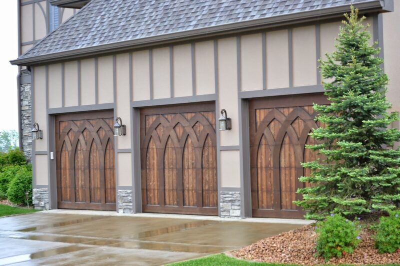 closeup of three garage doors that are custom wood with arched pieces on them to create a depth