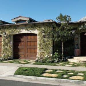 two ranch house custom wood residential garage doors on a stone home covered in green ivy