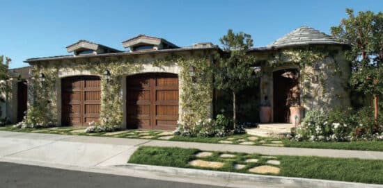 two ranch house custom wood residential garage doors on a stone home covered in green ivy