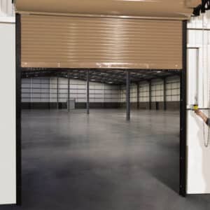 brown commercial rolling fire garage door opening up to an empty warehouse