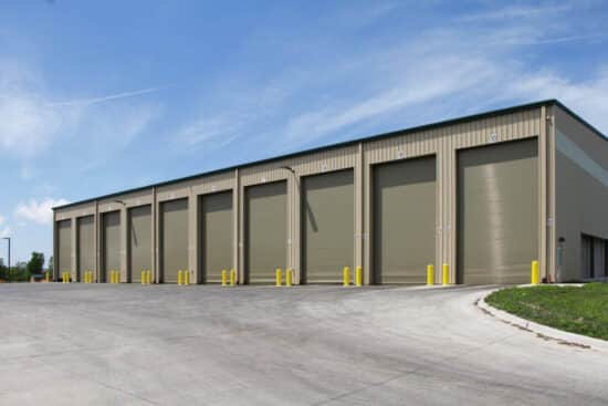 multiple tall and long commercial rolling garage doors on the exterior of a warehouse