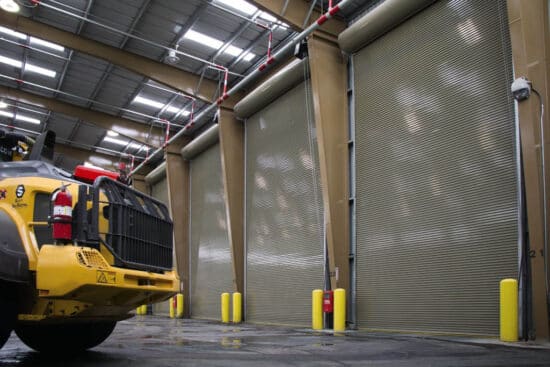 large and tall commercial rolling garage doors in a warehouse setting with a work truck in the foreground