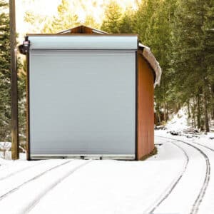 exterior view of a commercial rolling door on a small container building in a snowy setting somewhere in a forest