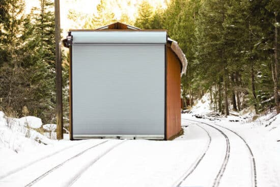 exterior view of a commercial rolling door on a small container building in a snowy setting somewhere in a forest