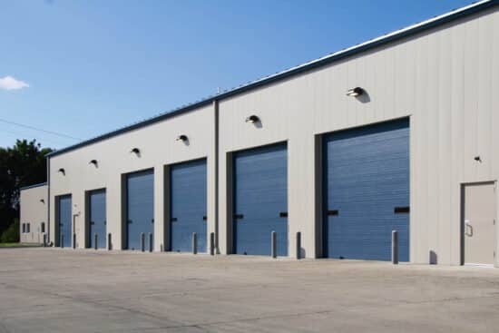 multiple blue commercial garage doors on a warehouse building