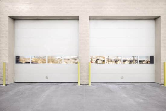 two commercial garage doors on a commercial building with yellow safety stands