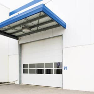 commercial garage doors on a warehouse building being covered by a blue awning