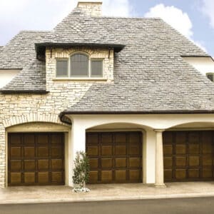 large stone home in san antonio with three custom wood garage doors