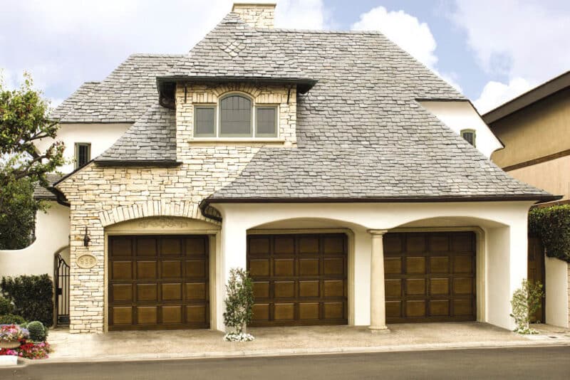 large stone home in san antonio with three custom wood garage doors