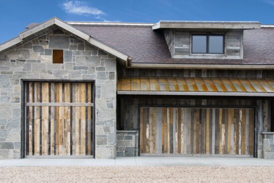 grey-toned home with two large, different sized garage doors made out of custom wood pieces, wood showing different colors