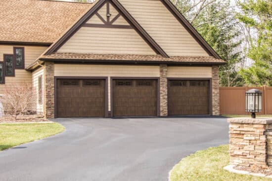 residential home with three faux wood grain style, sonoma/sonoma ranch panel garage doors