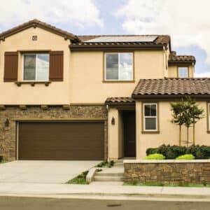large cream colored home in san antonio with a cream colored carriage style, sonoma/sonoma ranch panel residential garage door