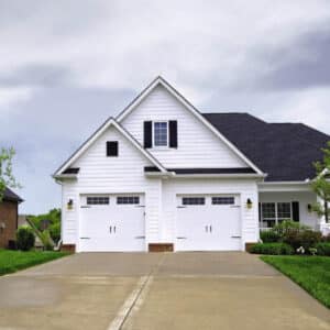 tall white home with two white carriage style sonoma/sonoma ranch panel garage doors that have a group of windows on the top rows