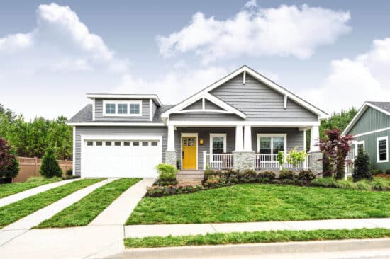 zoomed out view of a grey home with white features and white carriage style sonoma/sonoma ranch panel garage door that has a window in each panel on the top row