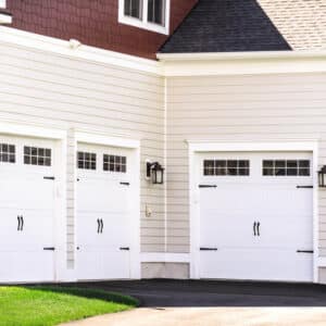 closeup of a san antonio home with three white carriage style, sonoma/sonoma ranch panel residential garage doors
