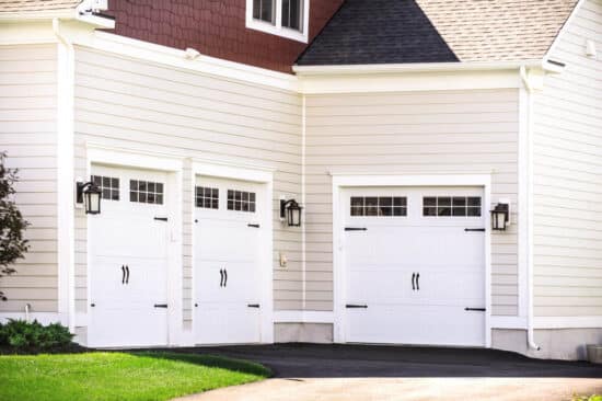 closeup of a san antonio home with three white carriage style, sonoma/sonoma ranch panel residential garage doors