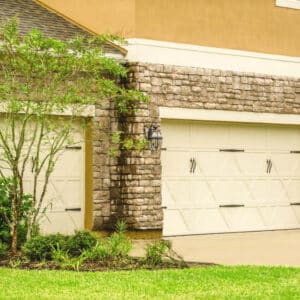 closeup of a san antonio home with two carriage style cream colored garage doors
