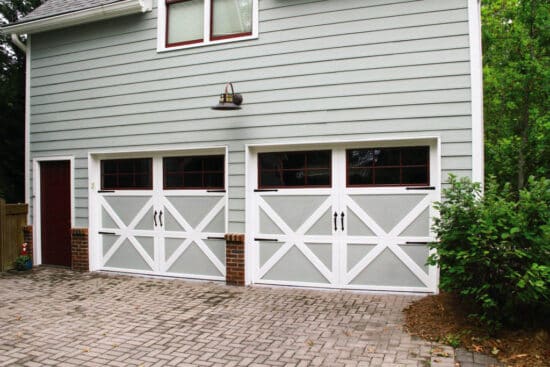 grey two-story guest house with two carriage style garage doors that have windows completely covering the entire top panel